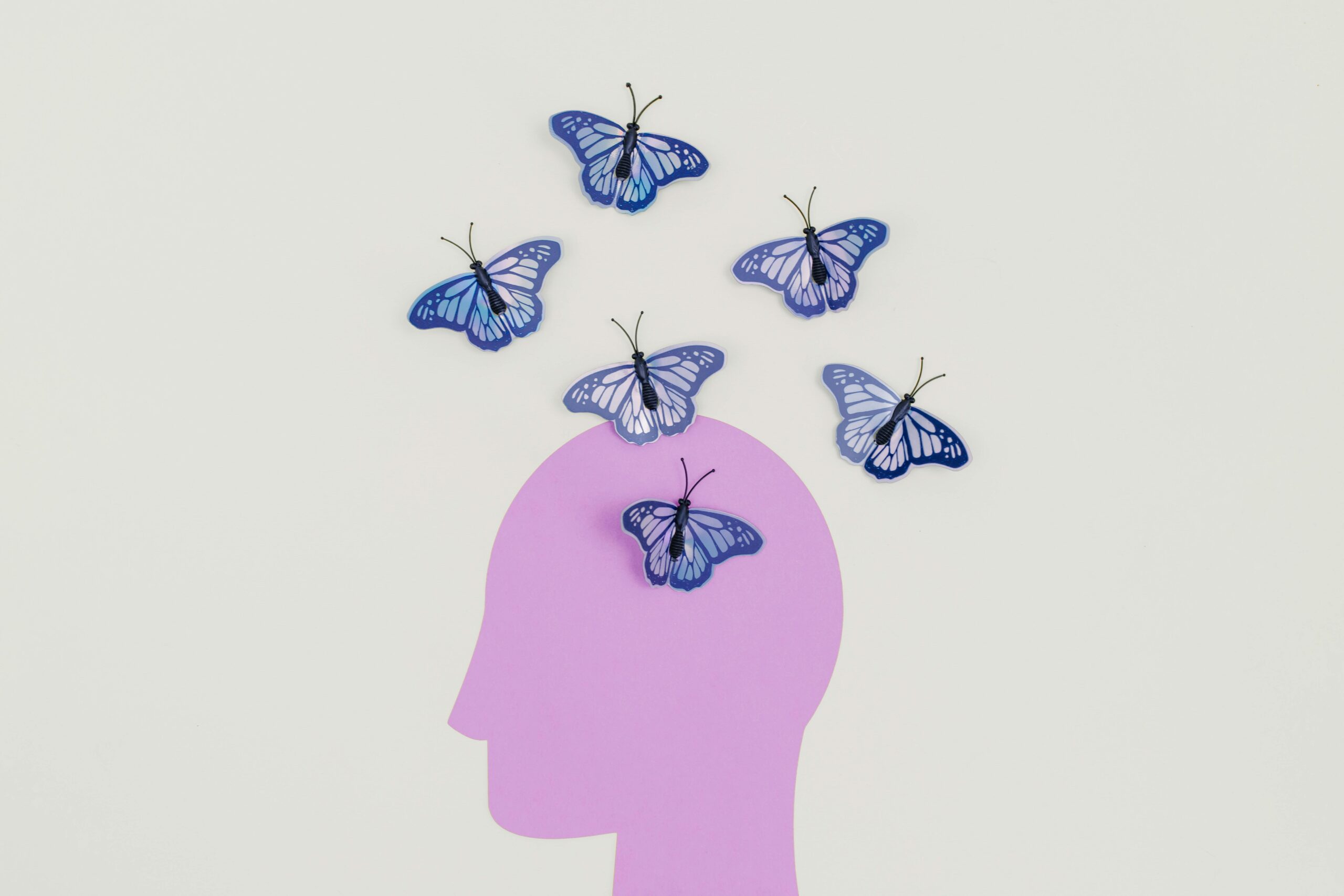 Purple silhouette with blue butterflies illustrating creative thoughts.